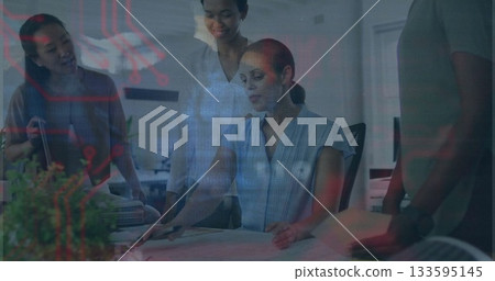 Reviewing blueprint, four women in business attire pointing to plan on office table, with tablet 133595145