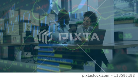 Professionals wearing business attire reviewing market data on laptop at wooden table in office 133595198