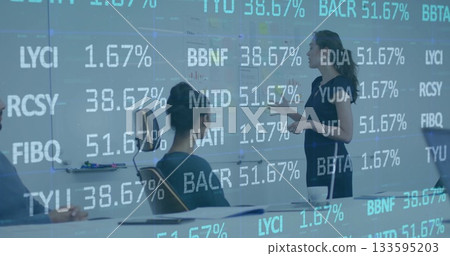 Presenting analyst in navy dress pointing at whiteboard in glass room with tickers, copy space 133595203