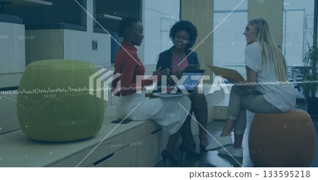 Discussing three female colleagues holding laptops and tan folder in office lounge, data overlay 133595218