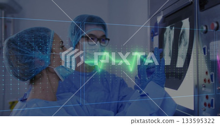 Examining two medics in blue scrubs studying Xray scans in imaging suite, with ECG hologram overlay 133595322