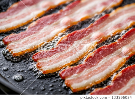 Crispy bacon in a frying pan with bubbling fat and sizzle 133596084
