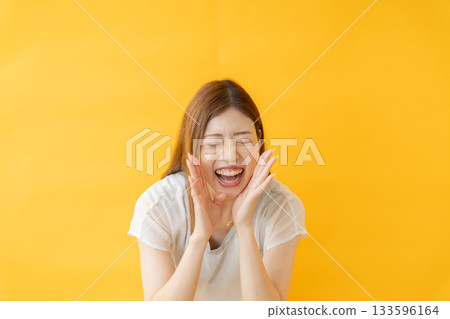 一名女子在黃色背景前歡呼 133596164