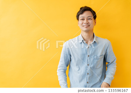 Smiling man in front of a yellow background Smiling man in front of a yellow background 133596167