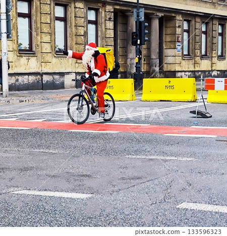 A person dressed as Santa Claus is riding a bicycle on a city street A person dressed as Santa Claus is riding a bicycle on a city street 133596323