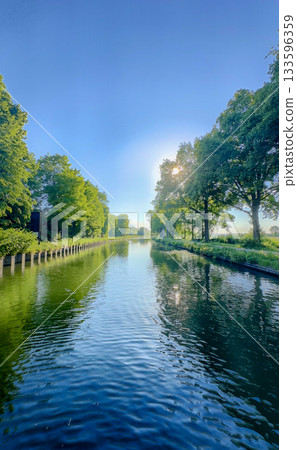 A Serene and Picturesque River Scene with Lush Greenery and a Clear Blue Sky Above A Serene and Picturesque River Scene with Lush Greenery and a Clear Blue Sky Above 133596359