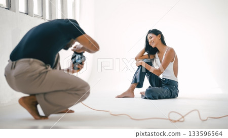 Photographer taking pictures of smiling model in photo studio Photographer taking pictures of smiling model in photo studio 133596564
