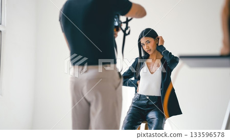 Photographer taking photos of fashion model posing in studio 133596578