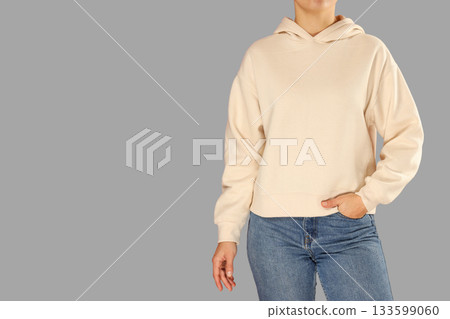 A person stands confidently wearing a casual hoodie and jeans 133599060