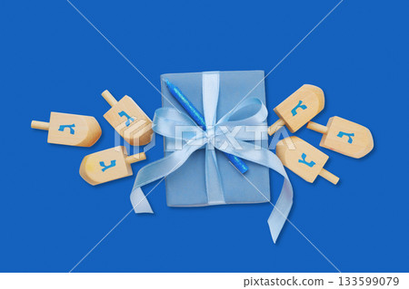 Hanukkah, gift box sits centered on a blue background with dreidels 133599079