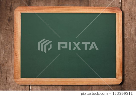 Framed green chalkboard resting against rustic plank backdrop in flat design, showing blank surface 133599511