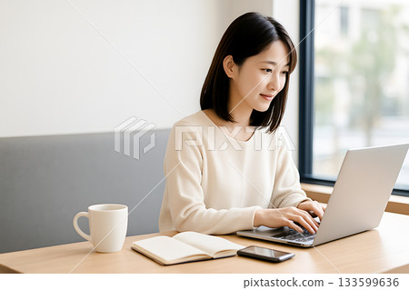 Business image of a young Japanese woman writing a blog and using SNS on a laptop in a cafe 133599636