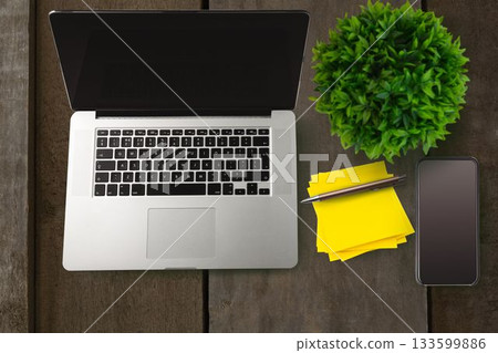 Silver laptop is sitting in flat design on wooden desk with smartphone, stationery items, plant Silver laptop is sitting in flat design on wooden desk with smartphone, stationery items, plant 133599886