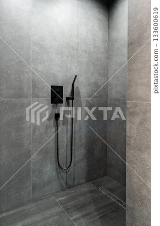 Modern black shower fixture in a stylish gray tiled bathroom space 133600619