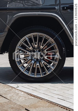 Close-up view of a luxury vehicle wheel on a modern pavement Close-up view of a luxury vehicle wheel on a modern pavement 133600626