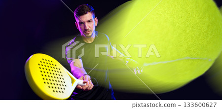 Man plays padel tennis with racket in dynamic motion on dark background 133600627