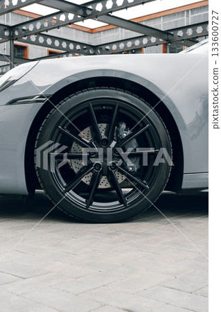 Stylish black alloy wheel on a sleek gray sports car at a modern urban location Stylish black alloy wheel on a sleek gray sports car at a modern urban location 133600727