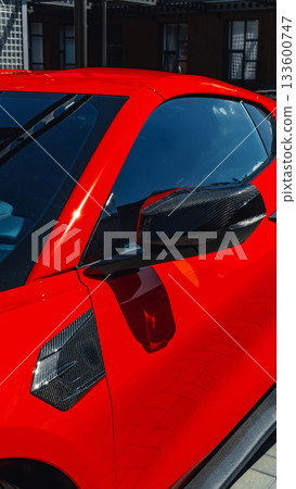 Bright red sports car showcased under clear blue sky in urban setting 133600747