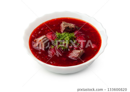 Rich and hearty beet soup served in a white bowl with fresh herbs on top 133600820