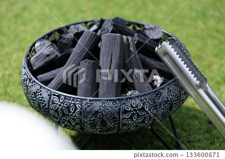 生火前準備的高品質木炭和火鉗,背景是草地。 生火前準備的高品質木炭和火鉗,背景是草地。 133600871