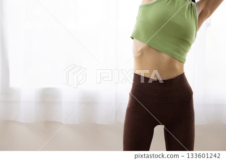Close-up of a woman's toned abdomen in fitness wear Close-up of a woman's toned abdomen in fitness wear 133601242