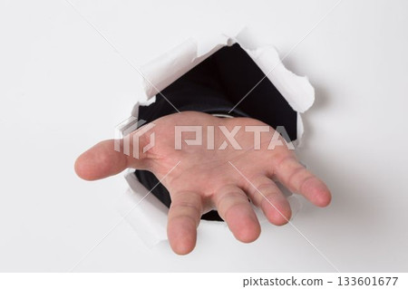 Hand ripping through paper 133601677