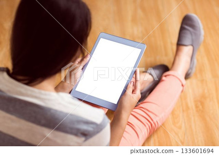Adult female is sitting on floor wearing gray slippers holding white screen tablet in flat design Adult female is sitting on floor wearing gray slippers holding white screen tablet in flat design 133601694
