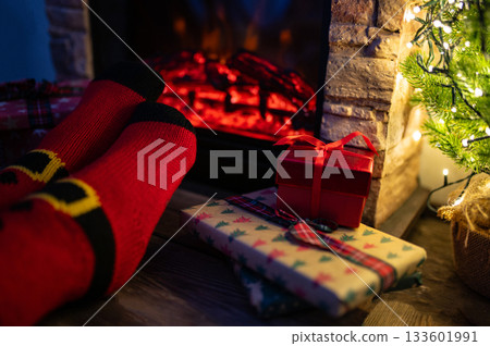 Woman legs with christmas socks and home interior with fireplace and dark wall background. Free space for your decoration. 133601991
