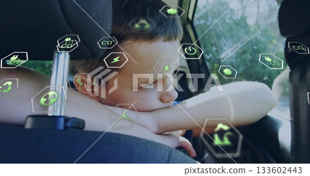 Leaning school-age boy gazing outside window in car back seat, with green energy icons 133602443