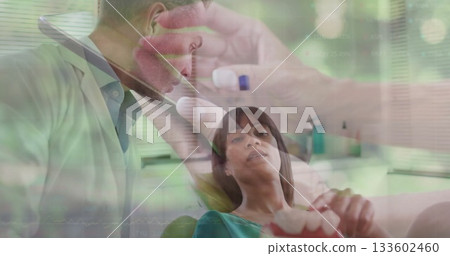 Leaning over patient dentist wearing white coat examining mouth in dental clinic, with dental mold 133602460