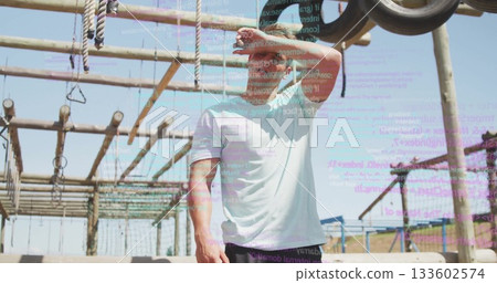 Shielding eyes fit man in athletic wear leaning back on outdoor obstacle course, with code overlay Shielding eyes fit man in athletic wear leaning back on outdoor obstacle course, with code overlay 133602574