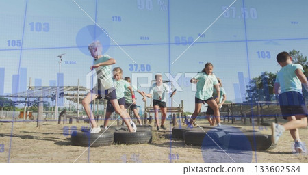 Instructor and children in sportswear stepping through tire obstacle course at park, with tires 133602584