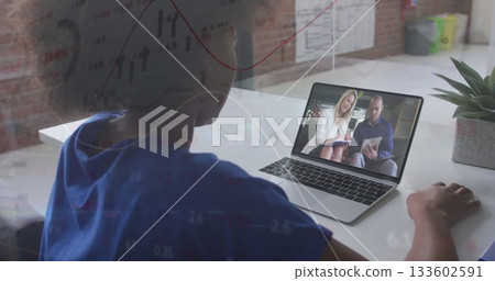 Joining call woman wearing blue Tshirt using laptop at desk, with tablet showing charts, copy space 133602591