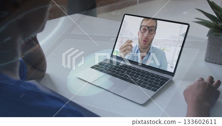 Woman wearing headphones joining meeting at home desk, with gesturing colleague on laptop and plant Woman wearing headphones joining meeting at home desk, with gesturing colleague on laptop and plant 133602611