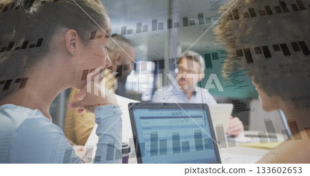 Analyzing team in business attire examining data on laptops and printed charts in meeting room Analyzing team in business attire examining data on laptops and printed charts in meeting room 133602653