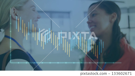 Discussing business women displaying digital bar chart overlay in office, with blue lanyards Discussing business women displaying digital bar chart overlay in office, with blue lanyards 133602671