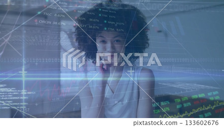 Smiling analyst leaning chin on hand at modern office with financial graphs, ticker symbols overlay 133602676