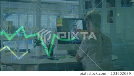 Discussing mature woman gesturing at pie chart on monitor at modern office desk, with grid overlay 133602689