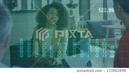 Leading discussion executive holding tablet at office lounge, with laptop data overlay in blazer 133602690