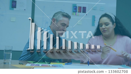 Analyzing colleagues reviewing printed charts and color swatches in office, with bar chart overlay Analyzing colleagues reviewing printed charts and color swatches in office, with bar chart overlay 133602708