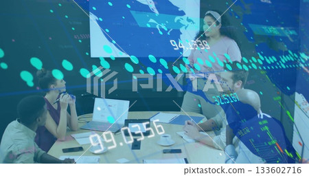 Showing professional in blouse presenting financial data at boardroom, with table, laptops, display 133602716