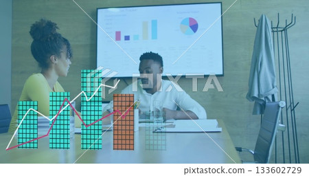Mid adult coworkers wearing business casual, reviewing charts on screen and documents in boardroom Mid adult coworkers wearing business casual, reviewing charts on screen and documents in boardroom 133602729