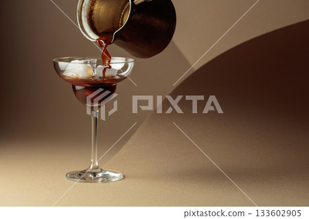 Black coffee is poured into a glass with ice. Black coffee is poured into a glass with ice. 133602905