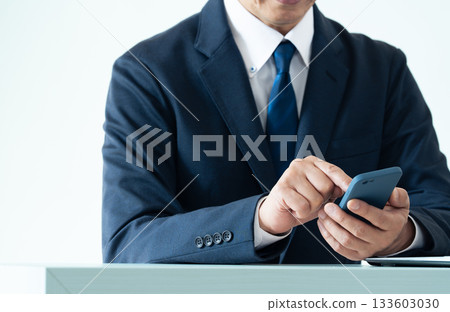 A businessman operating a smartphone 133603030
