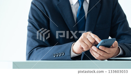 A businessman operating a smartphone 133603033