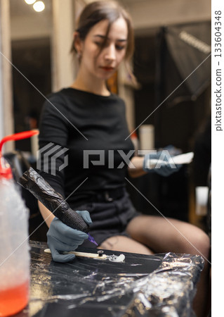 tattoo artist in gloves holding a tattoo machine during a session, preparing tools in a professional studio environment. tattoo artist in gloves holding a tattoo machine during a session, preparing tools in a professional studio environment. 133604348