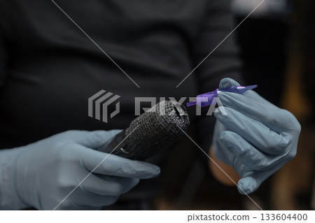 tattoo artist in gloves preparing a tattoo machine, attaching a sterile needle cartridge before a session in a professional studio. tattoo artist in gloves preparing a tattoo machine, attaching a sterile needle cartridge before a session in a professional studio. 133604400