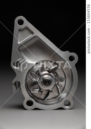High-quality spare parts for your car. Car maintenance. New water pump for the engine cooling system on a gray gradient background. High-quality spare parts for your car. Car maintenance. New water pump for the engine cooling system on a gray gradient background. 133604556