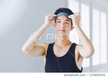 Young man wearing a hair band looking in the mirror 133604581