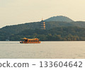 Wooden tourist boat navigate west lake in Hangzhou, China near pagoda temple on hill at dusk 133604642